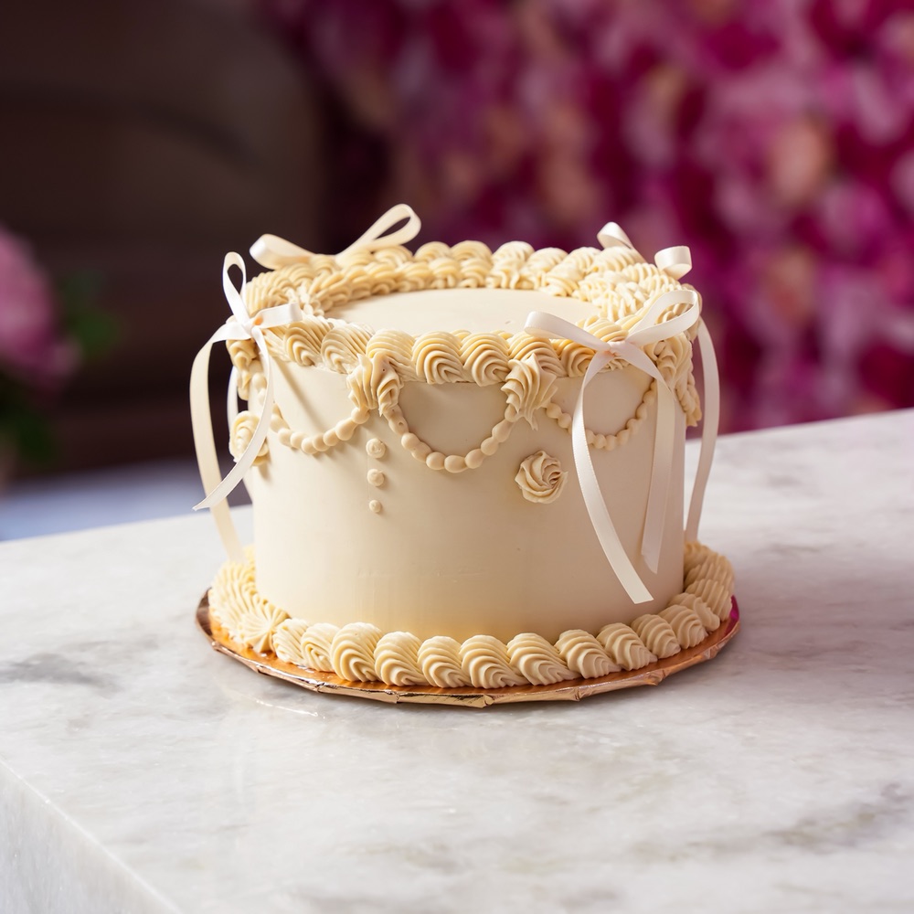 Cream cake with sculpted piping and bows by Cakes by Glorimar